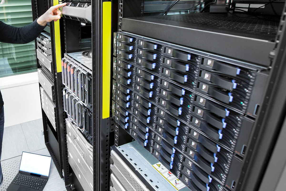Hand reaching for a server blade in a rack of storage drives